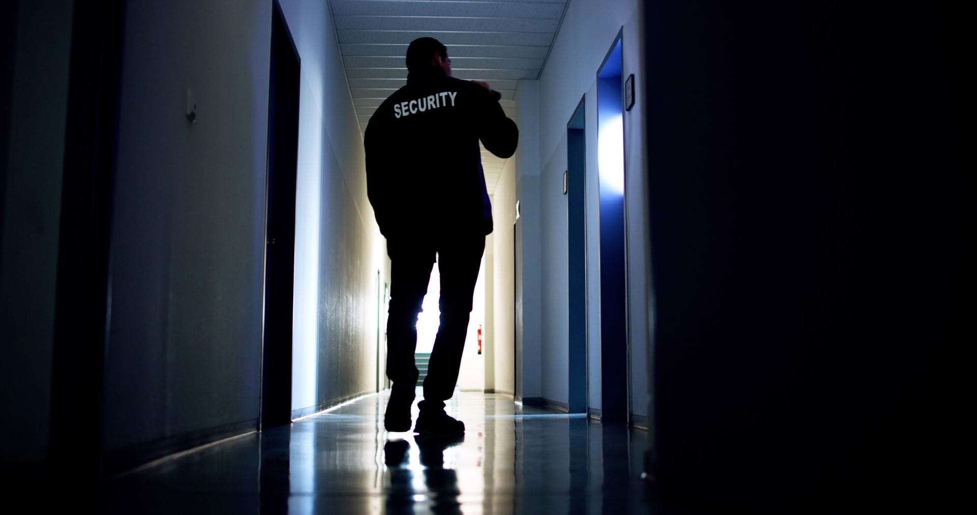 Security guard silhouetted in a building corridor